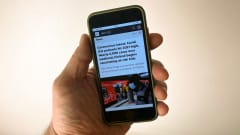 Hand holding a smartphone which is displaying the Yle News website.