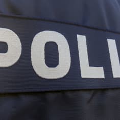 Poliisi teksti poliisihenkilön selässä.