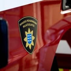 Pohjois-Pohjanmaan pelastuslaitoksen logo hihassa ja palo-autojen kyljessä.