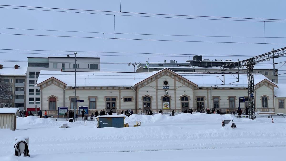 Oulun rautatieasema ja matkustajia laiturilla odottamassa junaa.