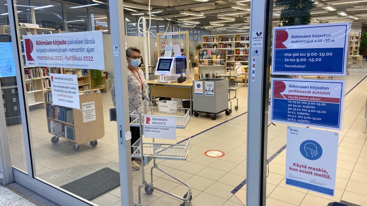 Kauppakeskuksessa väistötiloissa oleva Riihimäen kirjaston ovensuu. Avoimesta ovesta näkyy virkailija ja kirjahyllyjä.