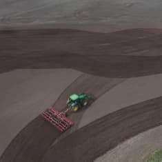 Ilmakuva, jossa traktori äestää peltoa.