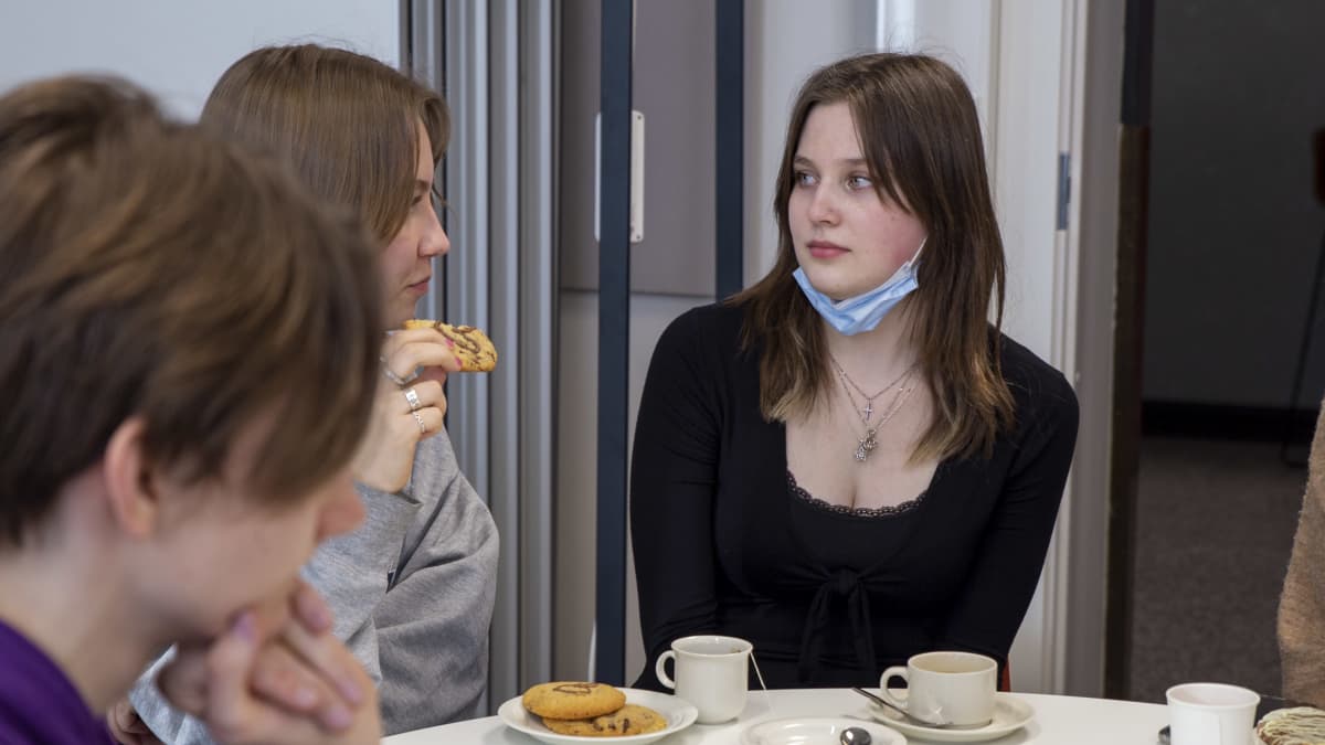Linnea Laurila Etu-Töölön lukiosta istuu kahvilla opiskelutovereidensa kanssa.