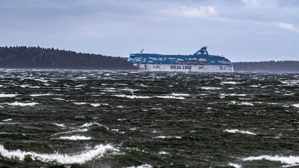 Tallink Siljas blåvita passagerarfartyg Galaxy försvinner bakom en ö under en höststorm med vita toppar på vågorna.