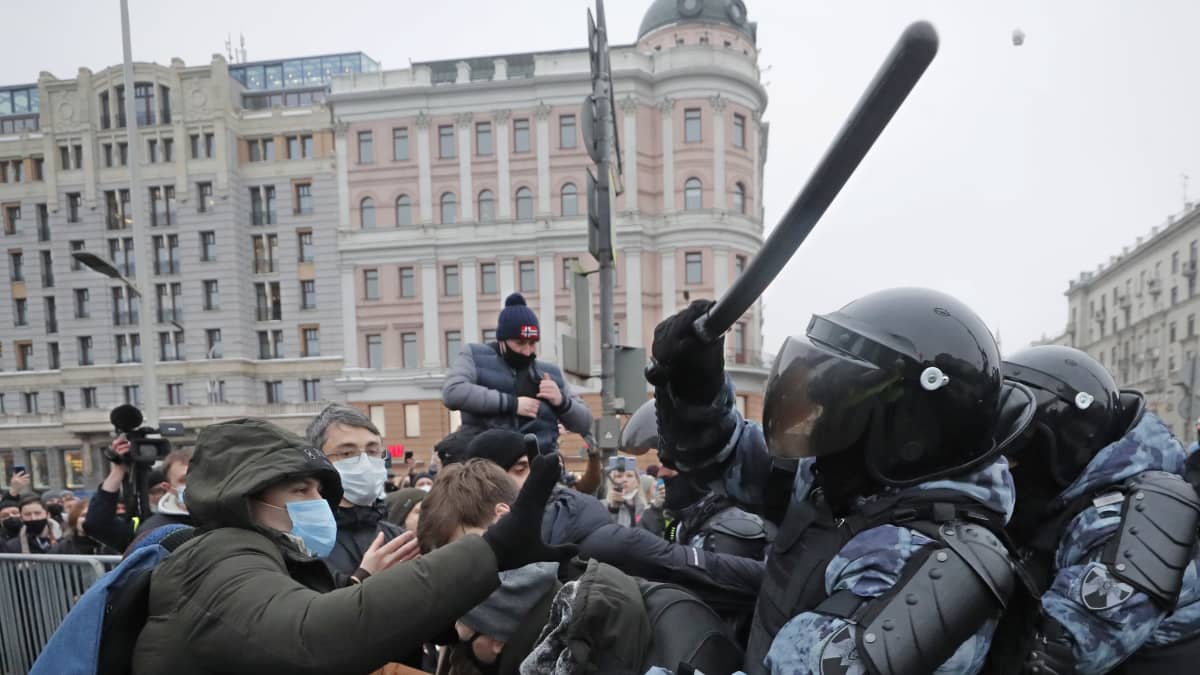 Poliisi lyö pampulla mielenosoittajaa, taustalla poliiseja ja mielenosoittajia