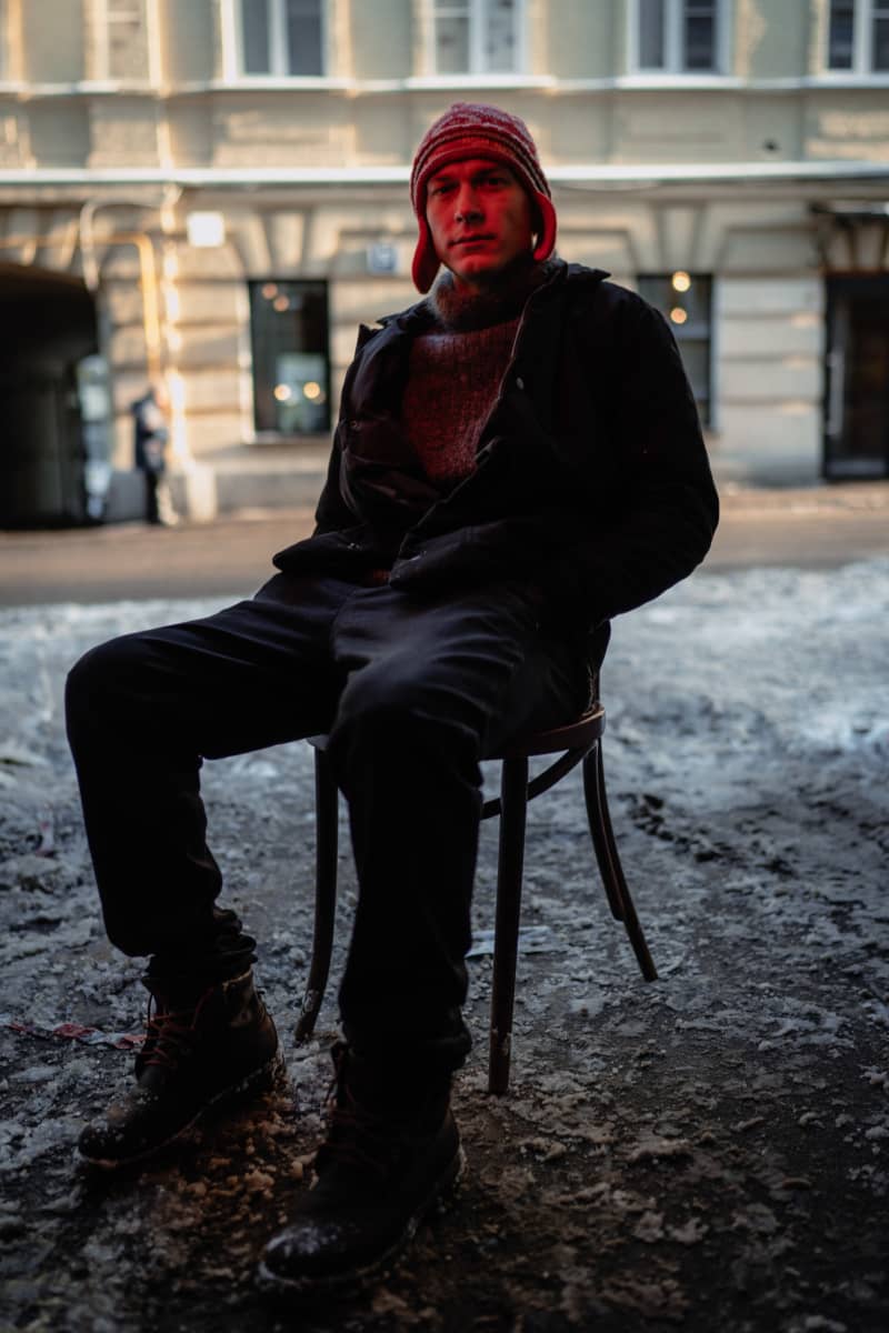 Näyttelijä Juri Borisov istuu tuolilla kadulla, kasvoillaan punainen valo.