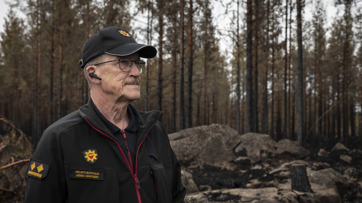 Pelastusjohtaja Jarmo Haapanen taustallaan palanutta metsää. 