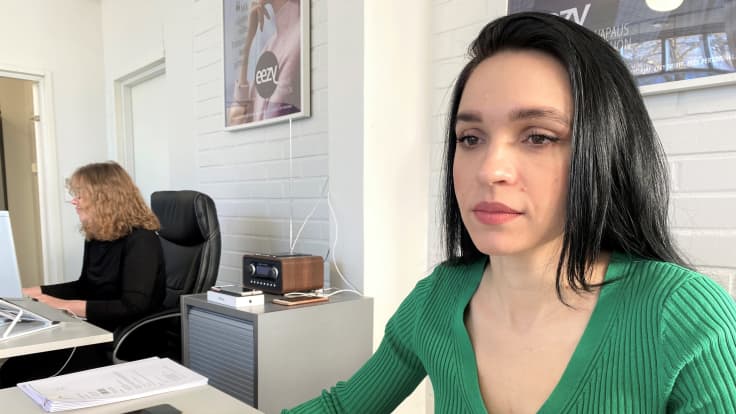 Kaksi naista tekee töitä toimistossa. Lähikuvassa oleva työntekijä katsoo tietokoneen ruutua ja ohi kamerasta. Paikka henkilöstöpalveluyritys Eezy Lahti. 