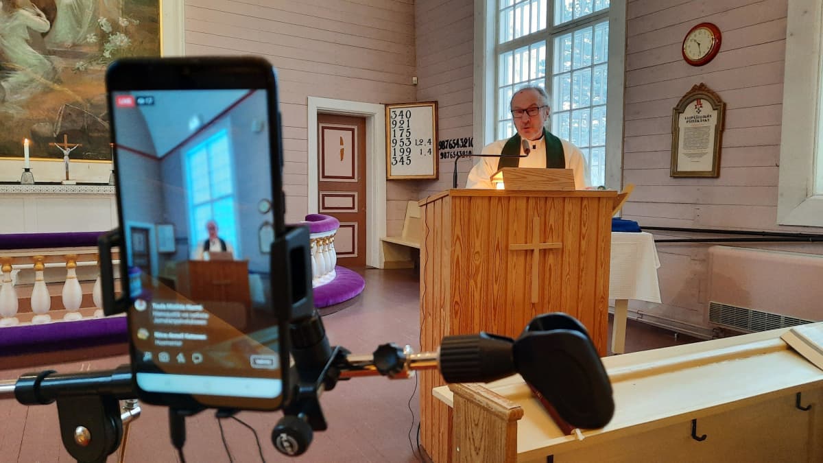 Kamera kuvaa kun pappi puhuu kirkossa