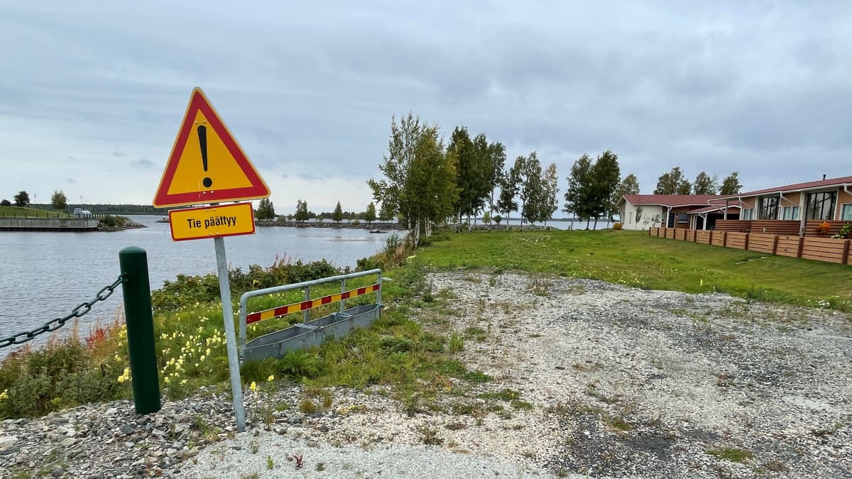 Tie päättyy -kyltti meren rannalla, rivitalon edustalla.