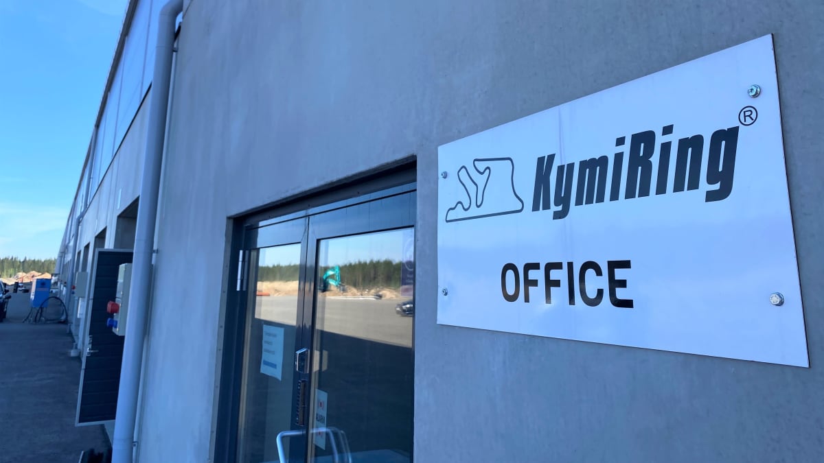 Harmaa rakennus, sisäänkäynti, kuva ulkoa, kyltti seinässä: Kymiring office
