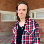 Abiturientti Matti Iisakki Musta seisoo koulun pihalla. 