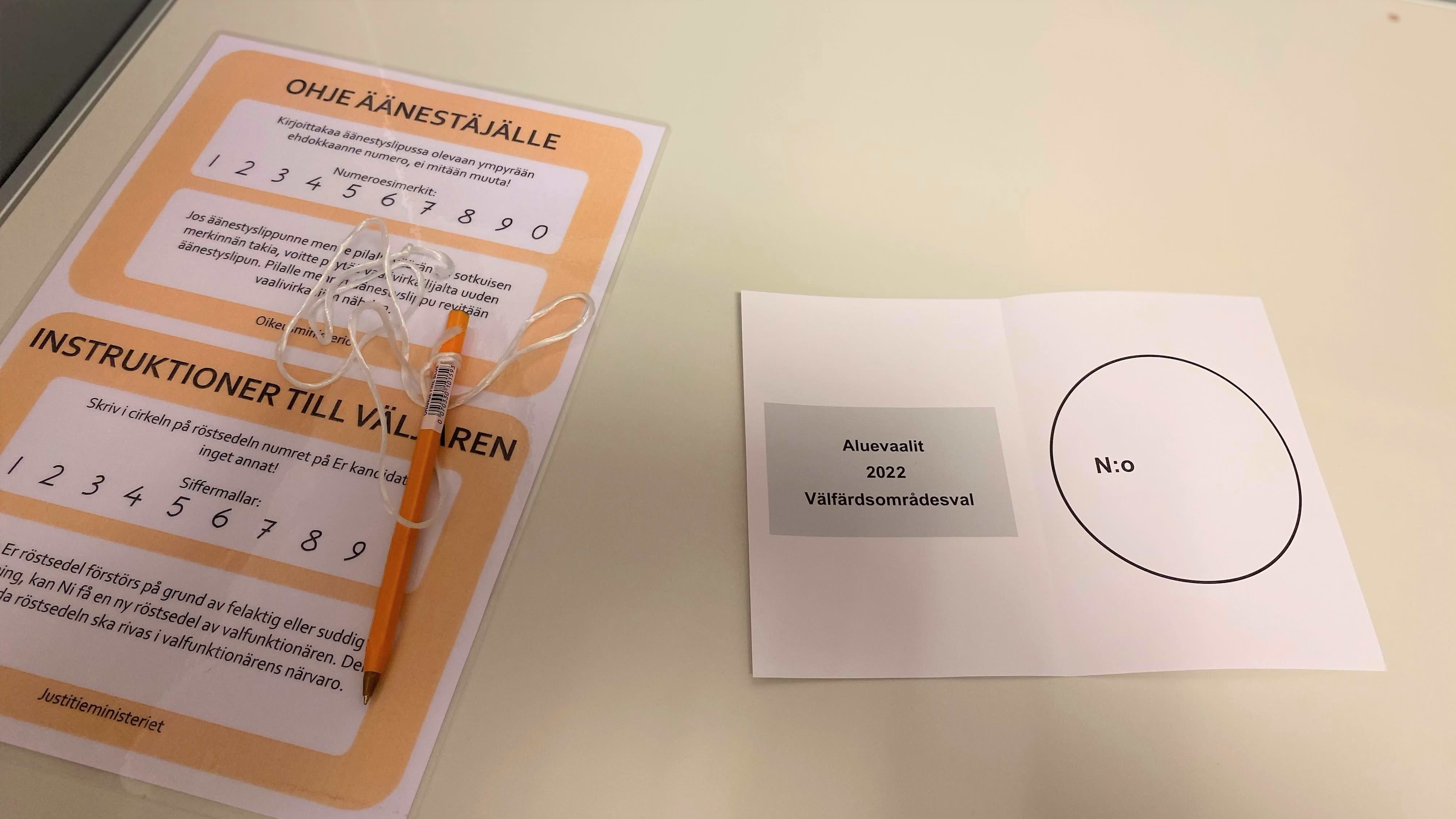 Aluevaalien 2022 äänestyslippu (tyhjä) pöydällä, vieressä kynä ja ohjelappu. 