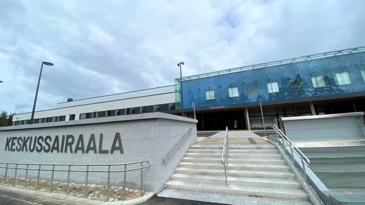 Lähikuva Päijät-Hämeen keskussairaalan sisäänkäynnistä, harmaa ja sininen betonirakennus.  Portaat sisäänkäynnille. 