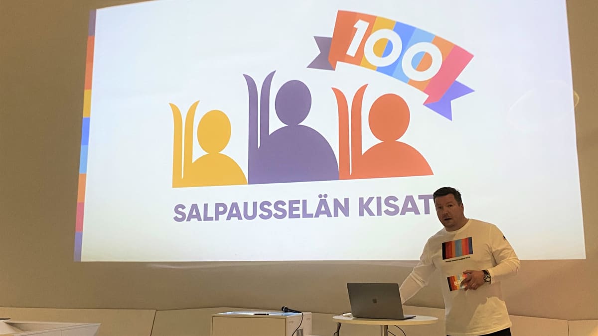Salpausselän kisojen pääsihteeri Tomi-Pekka Kolu esittelee 100-vuotisjuhlakisojen logoa. 