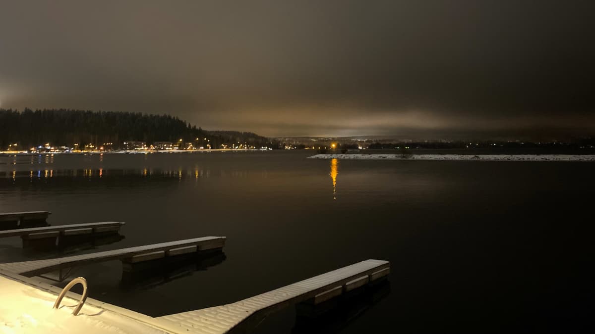 Lähikuva järvestä talvimaisemassa illalla. Järvi on Vesijärvi Lahdessa. Järven vastarannalla talojen valoja.