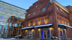 Lahden Sibeliustalon sisäänkäynti on lähikuvassa. Rakennuksen tiiliseinä on ulkoa valaistu.