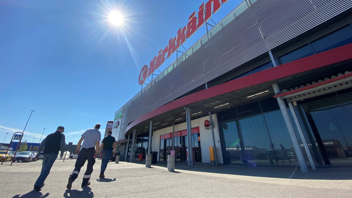 Miehet kävelevät kohti kauppakeskuksen ulko-ovea parkkipaikalta