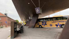 Lahden bussiterminaalin katos, vaalea bussi odottaa laiturilla, ihmisiä kulkee katoksen alla