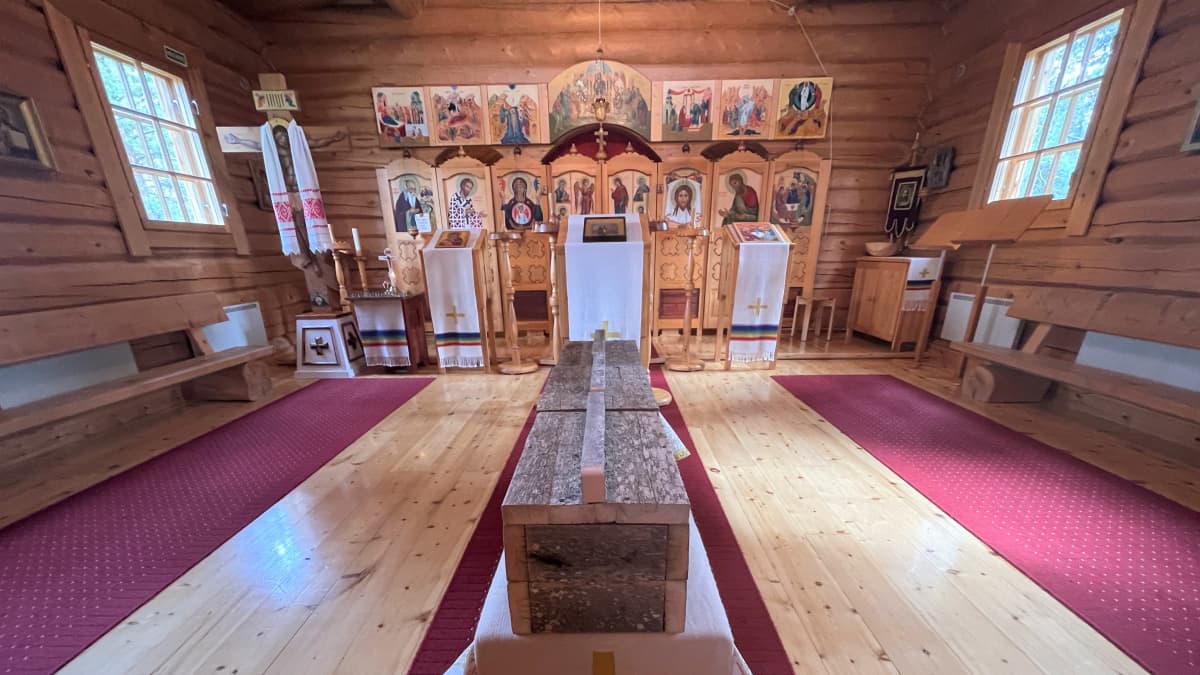 Kolme jäkälöityneestä laudasta rakennettua arkkua Nellimin ortodoksisen kirkon alttarin edessä.