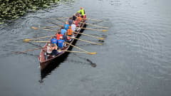 Ylhäältä päin kuvatussa kirkkoveneessä istuu neljätoista soutajaa ja kippari valmiina lähtemään liikkeelle.