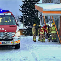 Palomiehiä ja pelastuslaitoksen johtoauto talvella kaupan pihassa.