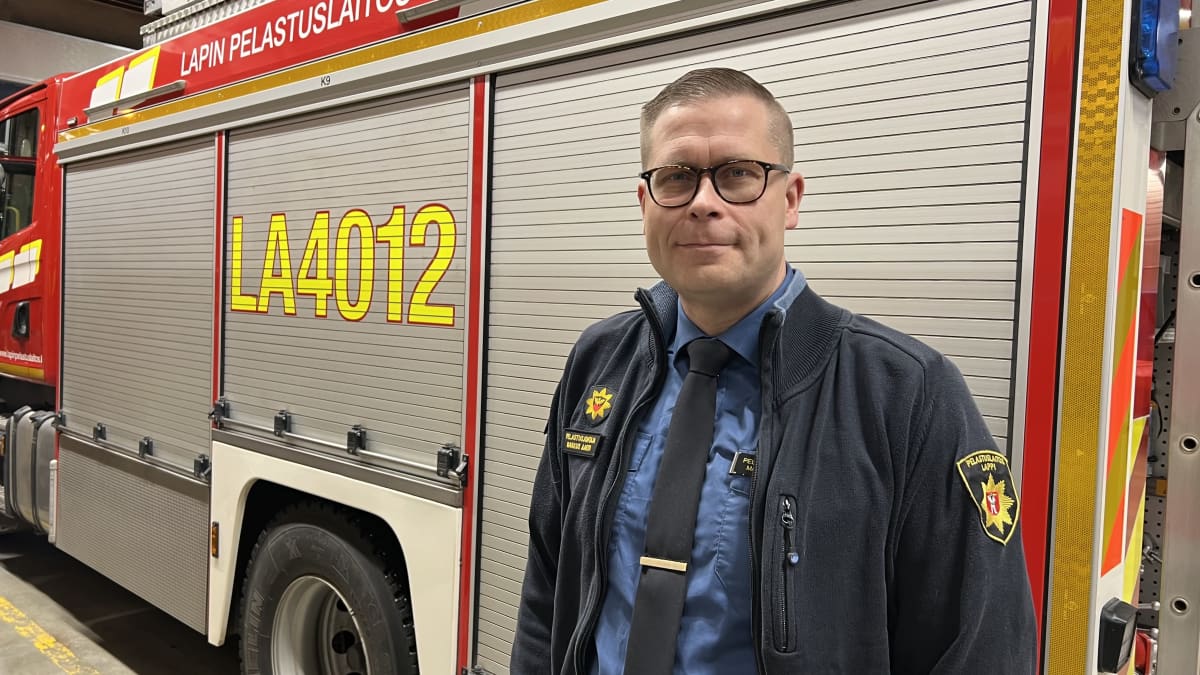 Pelastuslaitoksen siniseen takkiin pukeutunut pelastusjohtaja Markus Aarto  Lapin pelastuslaitokselta seisoo paloauton sivulla paloasemalla.