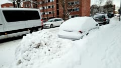 Lumikasaan hautautunut parkeerattu auto.
