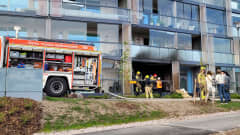 Kerrostaloasunto Espoon Kivenlahdessa syttyi tuleen. Kuvassa kerrostalon ulkosivu, vasemmalla paloauto ja oikealla ihmisiä. 
