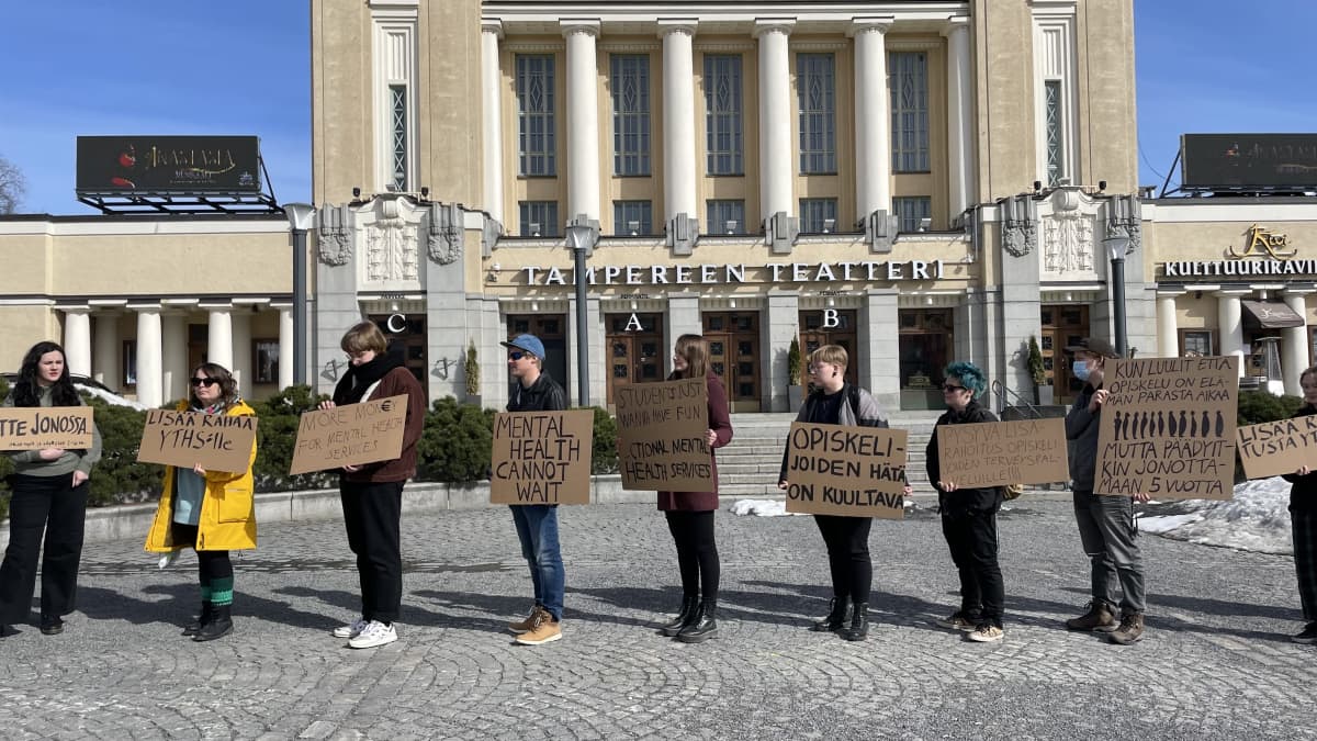 Mielenosoittajat seisoivat kylttiensä kanssa Tampereen keskustorilla.