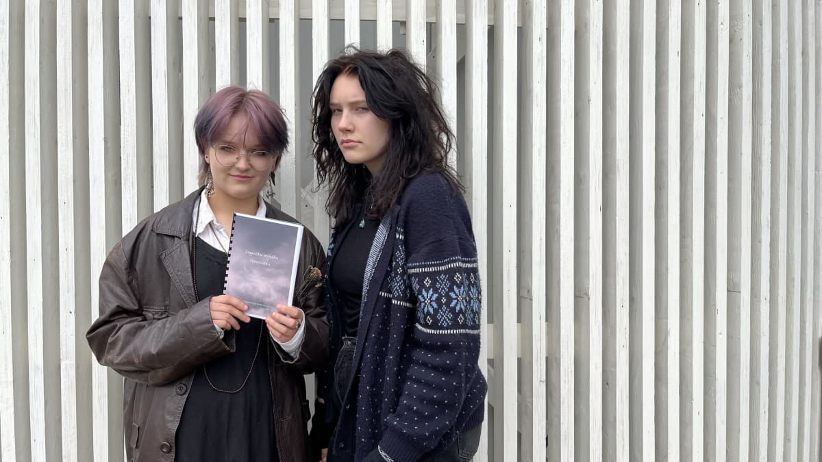 Emma Saari pitelee käsissään runokirjaa ja Kaisla Suominen seisoo hänen vieressään.