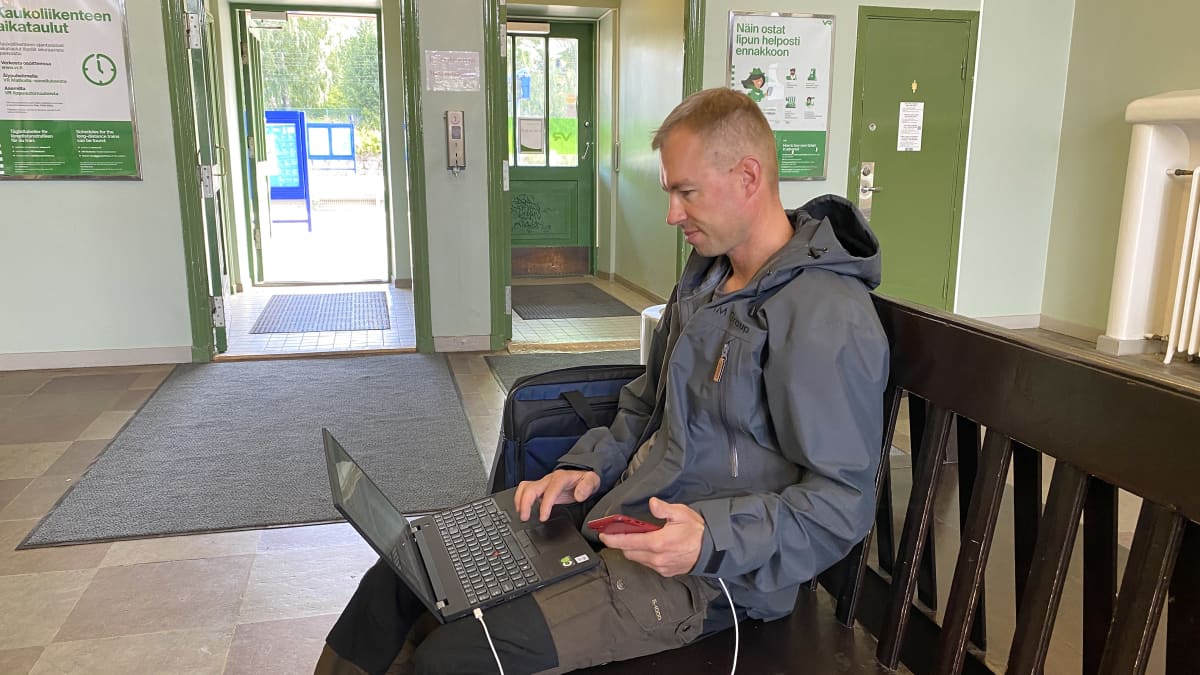 Antti Hanski istuu Hämeenlinnan rautatieaseman penkillä ja etsii tietoja läppäriltään.