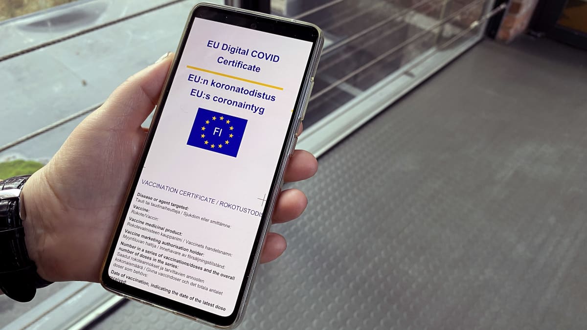 EU:n koronatodistus-teksti näkyy kädessä olevan kännykän näytöllä.