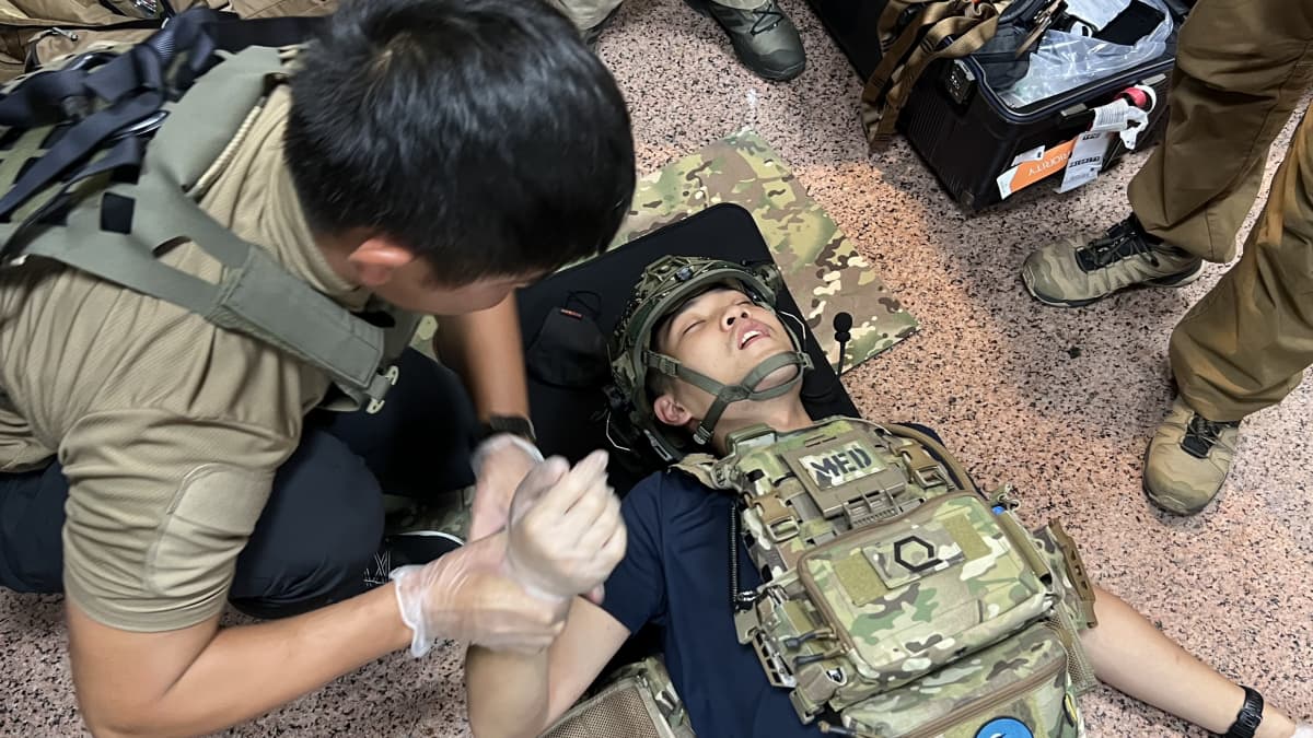 taistelupuvussa oleva taiwanilainen mies makaa lattialla 