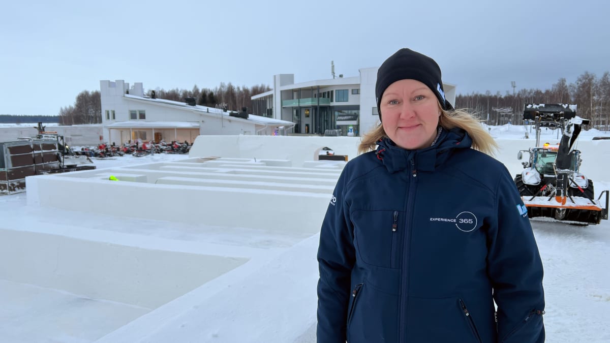 Etualalla siniseen toppatakkiin ja pipoon pukeutunut nainen Noora Barria. Hänen taustallaan näkyy luminen labyrintti ja valkoisia isoja rakennuksia.