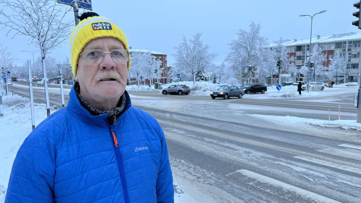 Lahtelainen Kari Kurkela Uudenmaankadun kävelytiellä, keltainen pipo päässä, sininen toppatakki yllään, katsoo kameraan, talvinen sää.