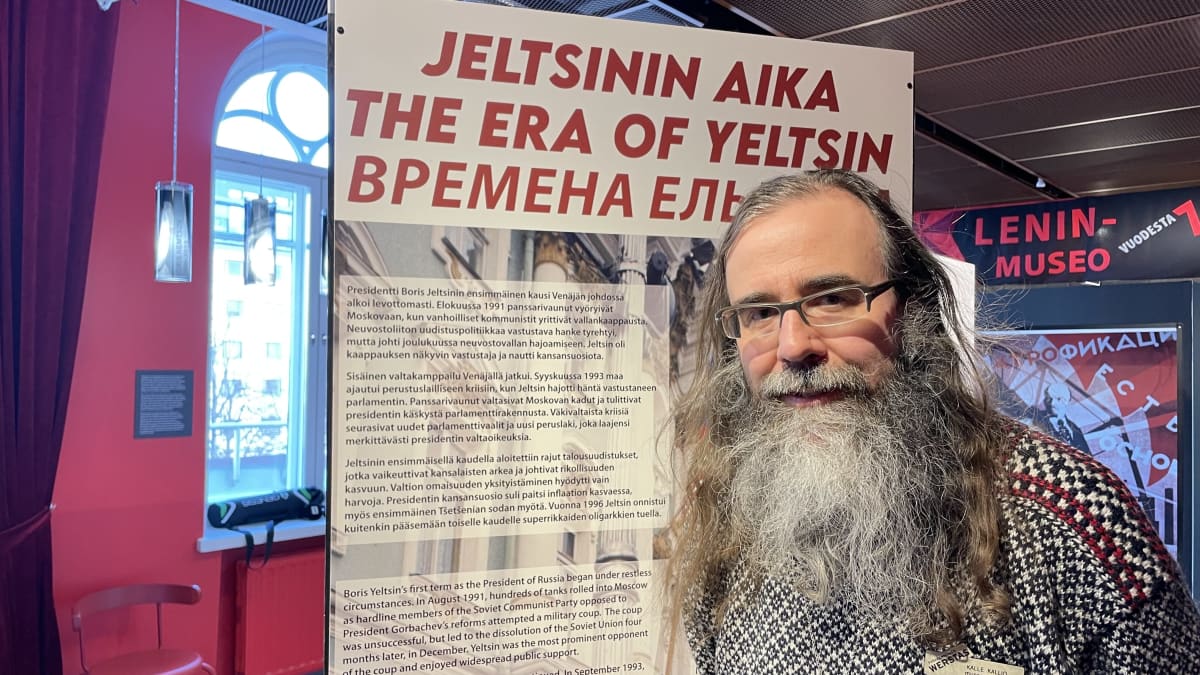 Museonjohtaja Kalle Kallio kuvattuna Lenin-museossa. Miehellä on pitkä, harmaa parta. Taustalla esittelytaulu, joka kertoo Jeltsinin ajasta. 