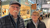 Hannu Liikka Ja Heli Liikka katsovat kameraan. Taustalla näkyy Tampereen kauppahallia.