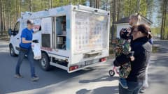 Jätskiauton myyjä Harri Taattola vie jäätelökassia autosta asiakkaille.