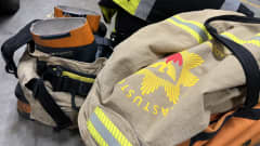 Palomiehen varusteet palolaitoksen hallin lattialla valmiina hälytystä varten.