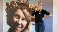 Eveliina Jukkola seisoo ison kuvan vierellä. Kuvassa on muumien luoja Tove Jansson.