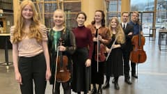 Sinfonia Lahden konserttiin soittamaan valitut seitsemän nuorta solistia jonossa Sibeliustalon Metsähallissa. Kahdella nuorella on viulu kädessään, yhdellä huilu ja takimmaisella miehellä sello.