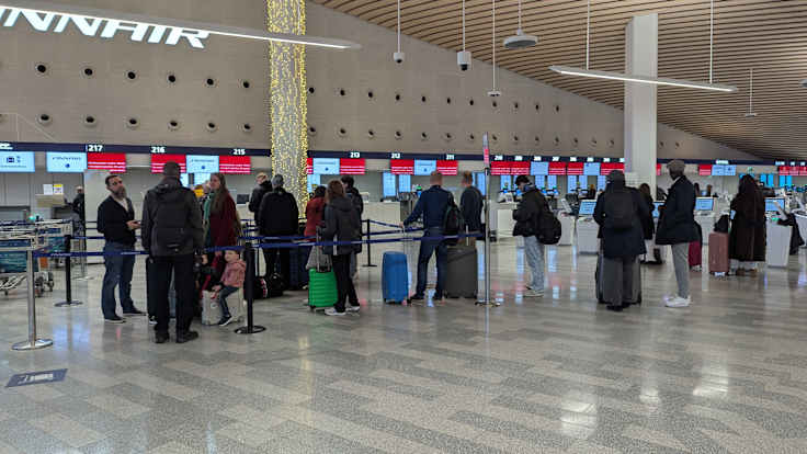 Photo shows people in a queue at Helsinki Airport.