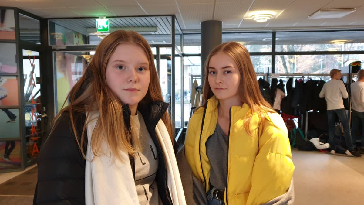 Kaksi tyttöä seisoo koulun aulassa