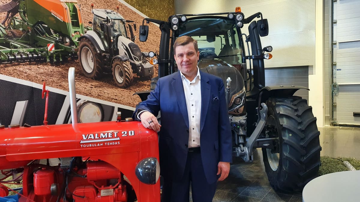 Valtran toimitusjohtaja Jari Rautjärvi poseeraa vanhan ja uuden traktorimallin edessä Valtran Suolahden tehtaalla.