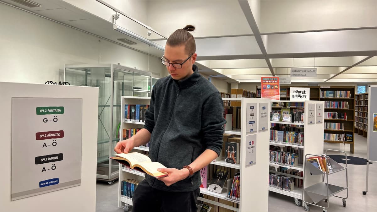 Kirjastovirkailija Miikka Virtanen lukee kirjaa Kouvolassa