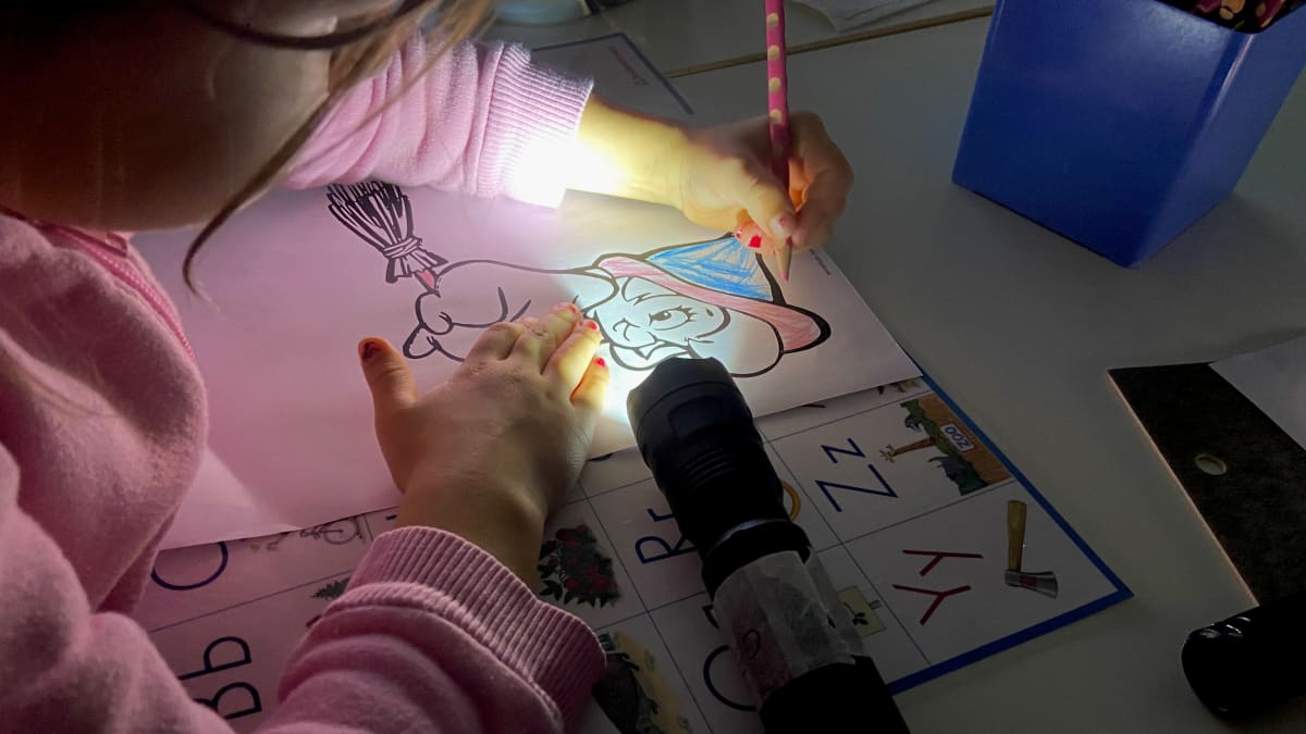 Lapsi piirtää taskulampun valossa.