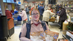 K-market Järvikansa kauppias Nina Hannonen seisoo kaupassa käsissään kaksi leipäpakettia. 