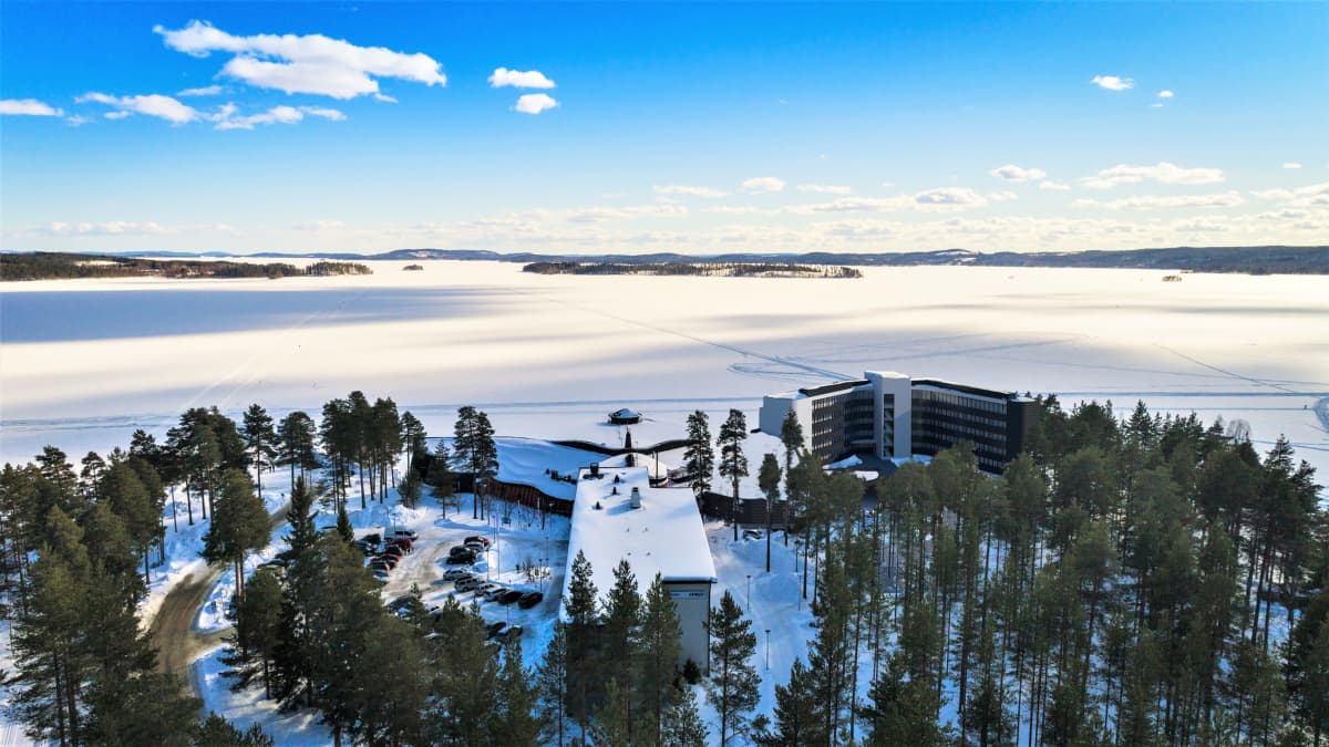 Kylpylähotelli talvisessa maisemassa järven rannalla.