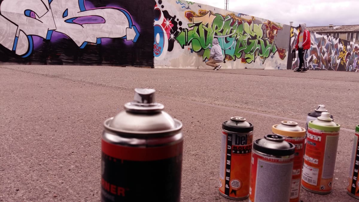 Sprayburkar som en graffitiartist använder på en vägg vid ett bygge.